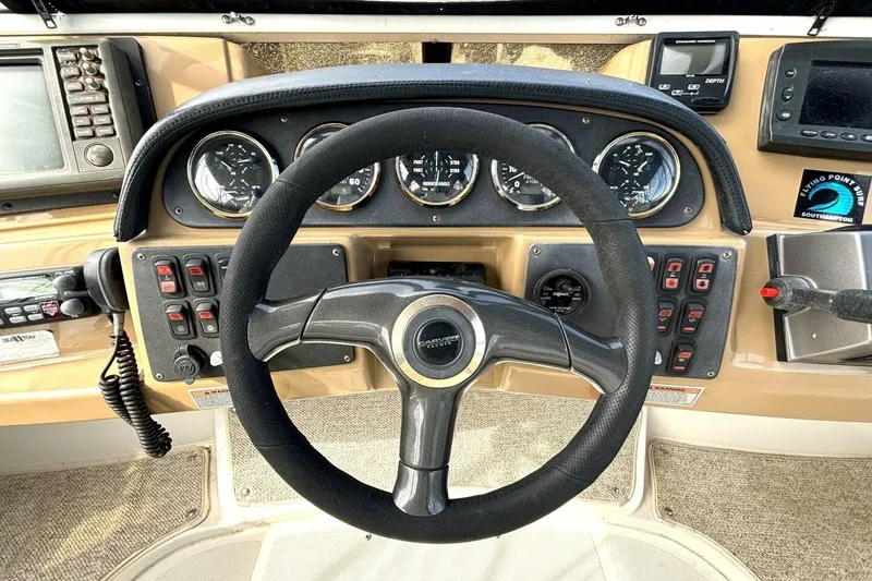 Slide: The Image of 2003 Carver 396 Motor Yacht helm with steering wheel, gauges, and navigation controls. - 25