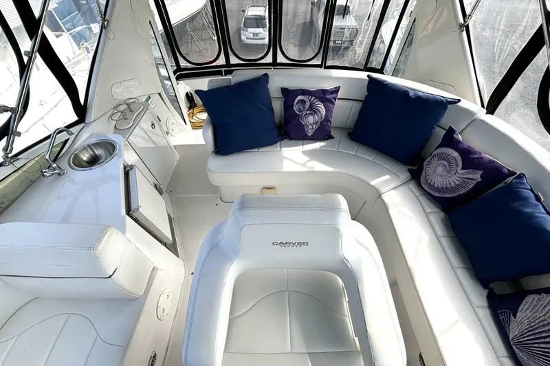 Slide: The Image of 2003 Carver 396 Motor Yacht interior with white seating, blue pillows, and a small sink. - 27