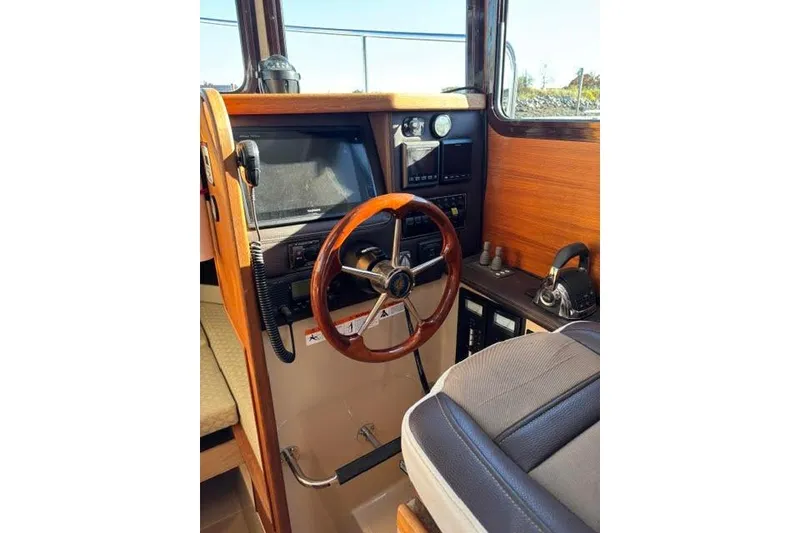 Slide: The Image of 2017 Ranger Tugs R-27 Tug helm with wooden steering wheel and navigation controls. - 10