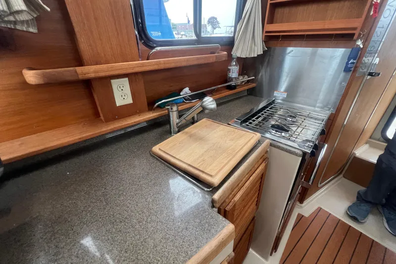 Slide: The Image of 2017 Ranger Tugs R-27 Tug kitchen with stove, countertop, and wooden cabinetry. - 13