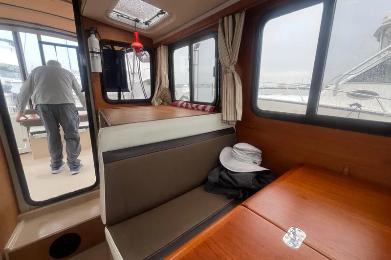 Slide: The Image of Interior of 2017 Ranger Tugs R-27 Tug with seating and windows, person standing outside. - 16