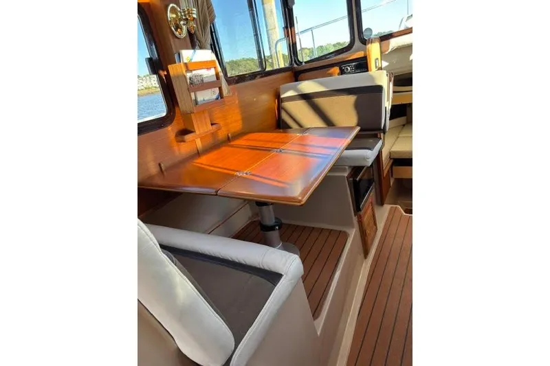 Slide: The Image of Interior of 2017 Ranger Tugs R-27 Tug with wooden table and seating. - 2