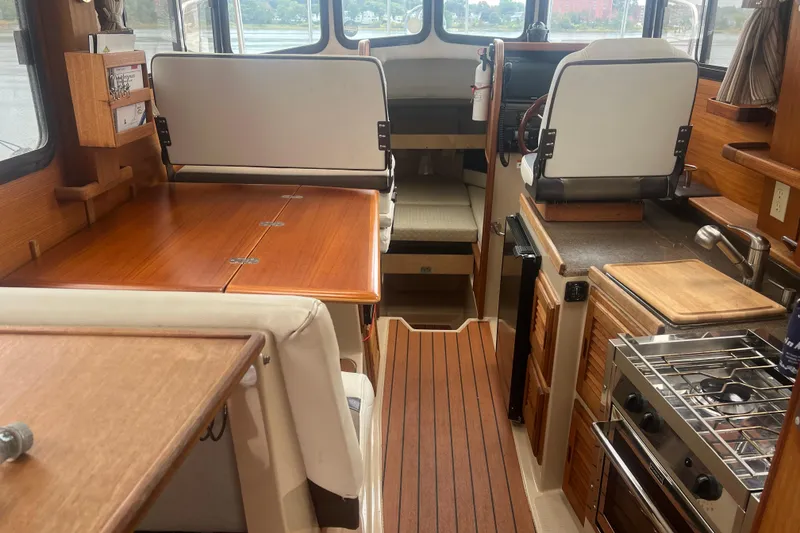 Slide: The Image of 2017 Ranger Tugs R-27 Tug interior with wood finishes, kitchen, and seating area. - 21