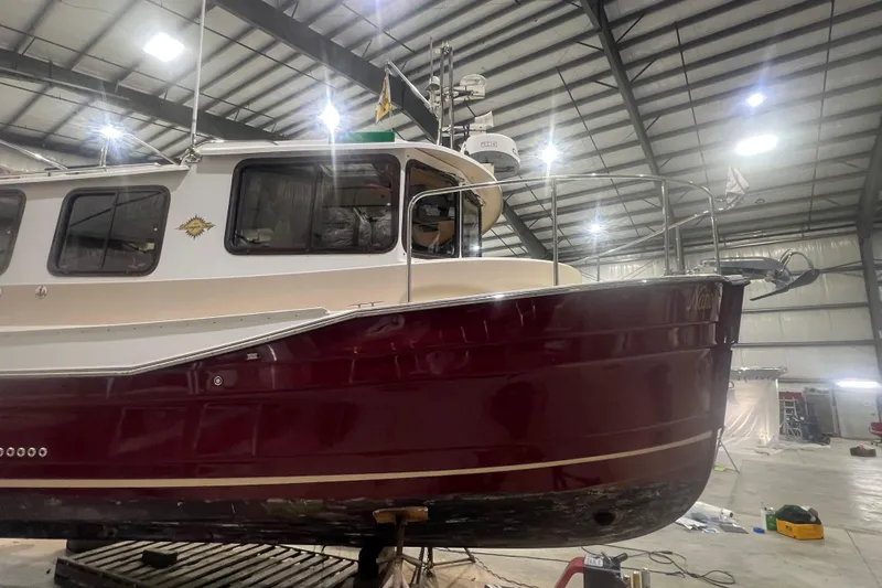 Slide: The Image of 2017 Ranger Tugs R-27 Tug in a warehouse, showcasing its maroon and white exterior. - 25