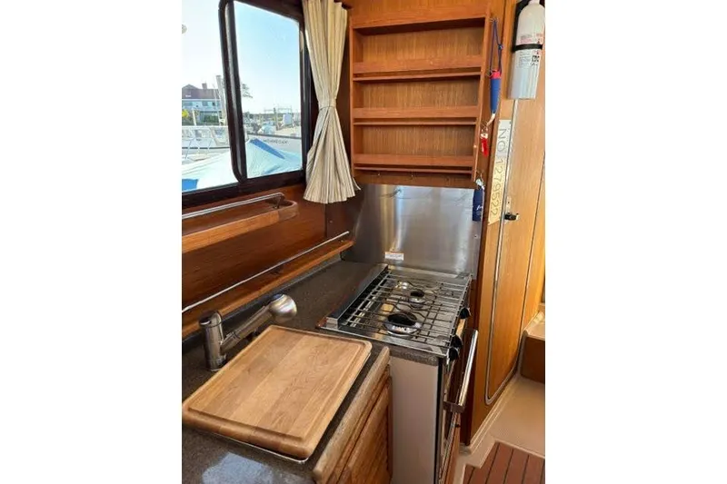 Slide: The Image of 2017 Ranger Tugs R-27 Tug kitchen with stove, sink, and wooden cabinetry. - 5