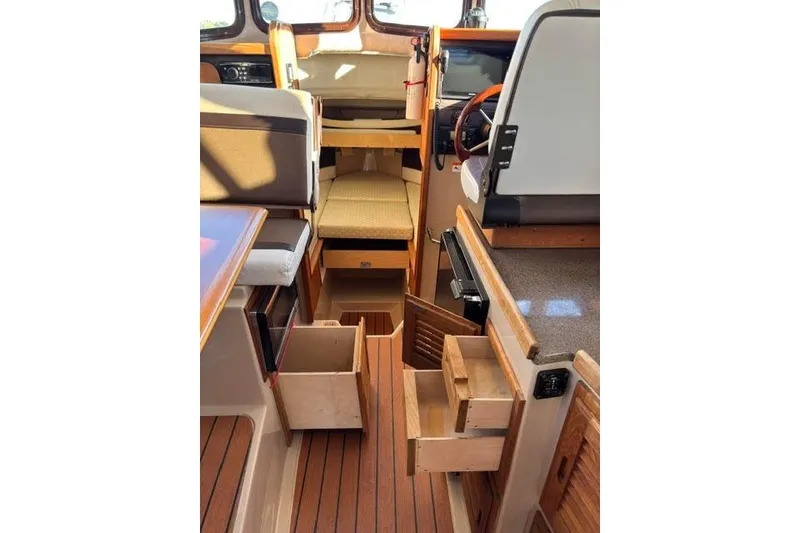 Slide: The Image of Interior of 2017 Ranger Tugs R-27 Tug with open wooden drawers and seating area. - 7