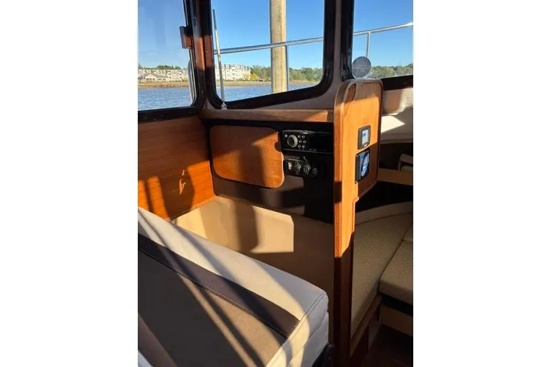 Slide: The Image of Interior of 2017 Ranger Tugs R-27 Tug, featuring wood paneling and seating by a window. - 9