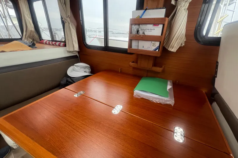 Slide: The Image of 2017 Ranger Tugs R-27 Tug interior with wooden table and navigation materials. - 15