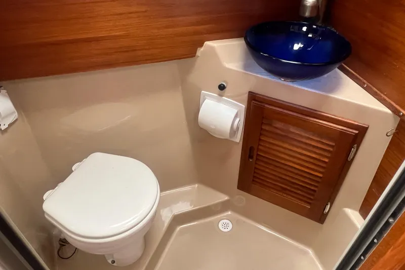 Slide: The Image of 2017 Ranger Tugs R-27 Tug bathroom with toilet, wooden cabinet, and blue sink. - 19