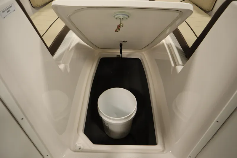 Slide: The Image of 2026 Yamaha Boats 222 FSH Sport storage compartment with a white bucket inside. - 16