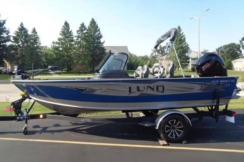 The Image of 2026 Lund 1875 Impact XS Sport boat on trailer, parked outdoors. - 0