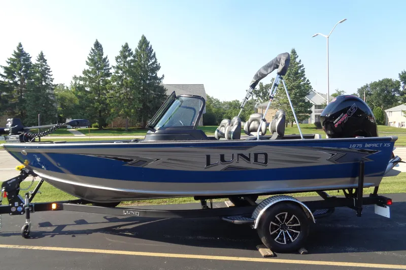 Slide: The Image of 2026 Lund 1875 Impact XS Sport boat on trailer, parked outdoors. - 1