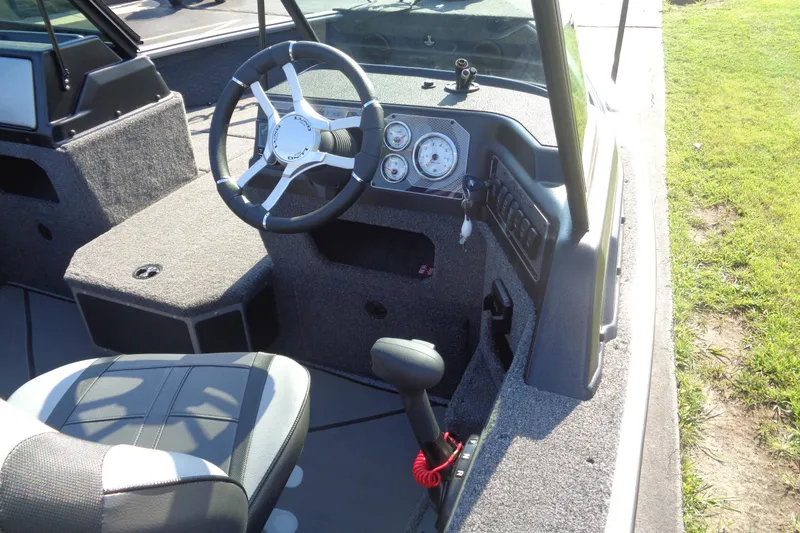 Slide: The Image of 2026 Lund 1875 Impact XS Sport boat interior with steering wheel and dashboard controls. - 10