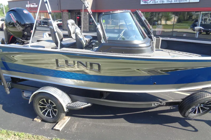 Slide: The Image of 2026 Lund 1875 Impact XS Sport boat on trailer, parked outside a building. - 8