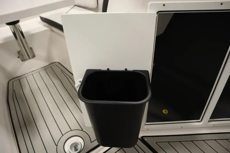 Slide: The Image of Yamaha 222 FSH Sport E 2026 boat interior with black trash bin and sleek flooring. - 24