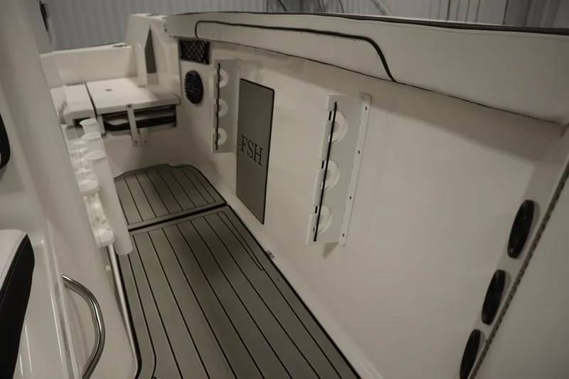 Slide: The Image of 2026 Yamaha Boats 222 FSH Sport E interior with rod holders and cushioned seating. - 27