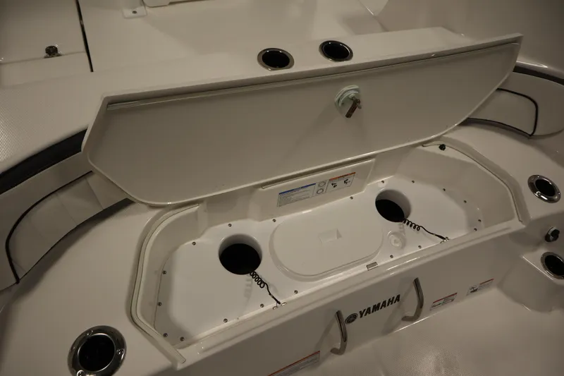 Slide: The Image of 2026 Yamaha Boats 222 FSH Sport E storage compartment with open lid and cup holders. - 48