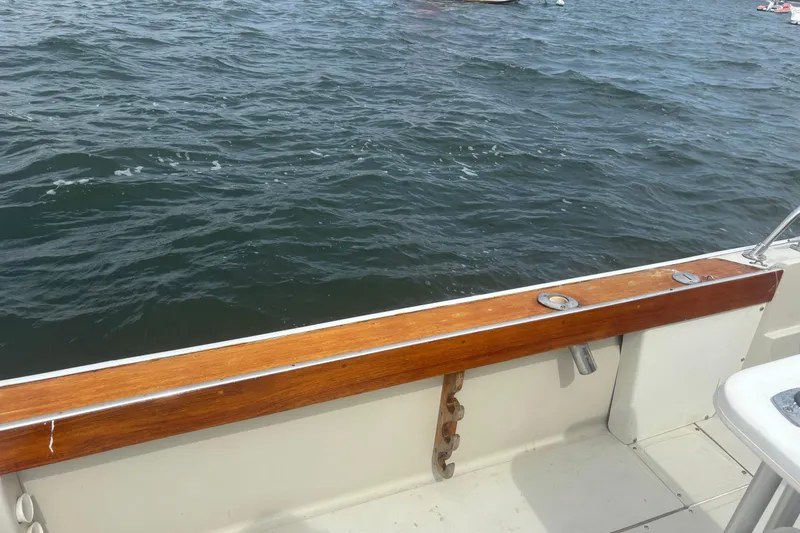 Slide: The Image of 1988 Boston Whaler 25 Outrage boat deck with wooden railing, overlooking water. - 11