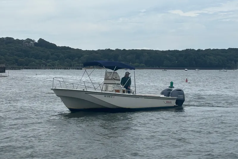 Slide: The Image of 1988 Boston Whaler 25 Outrage boat cruising on a lake with scenic forested background. - 2
