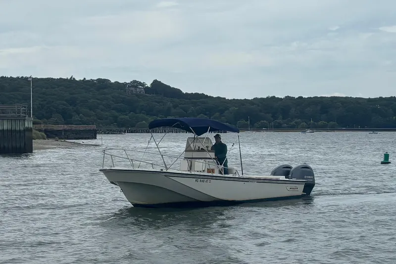 Slide: The Image of 1988 Boston Whaler 25 Outrage boat on water, with scenic shoreline background. - 5