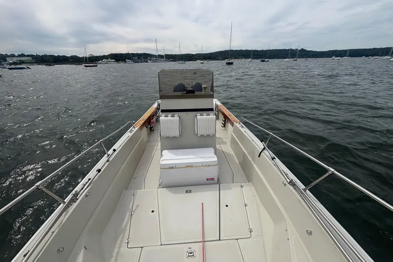 Slide: The Image of 1988 Boston Whaler 25 Outrage boat on calm water, featuring spacious deck and scenic view. - 7