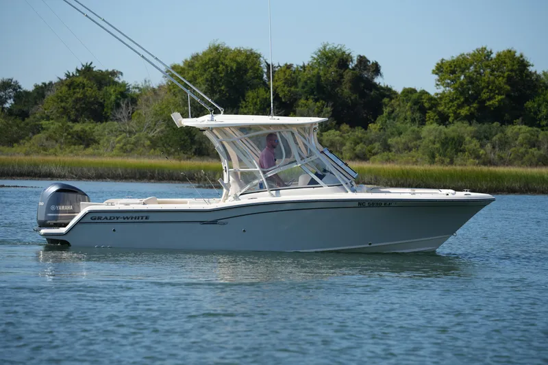 Slide: The Image of 2019 Grady-White Freedom 235 boat cruising on a calm lake with lush greenery. - 10
