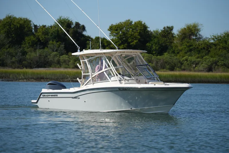 Slide: The Image of 2019 Grady-White Freedom 235 boat cruising on a calm lake with lush greenery. - 12
