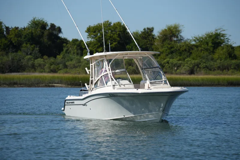 Slide: The Image of 2019 Grady-White Freedom 235 boat cruising on a serene lake with lush greenery. - 13