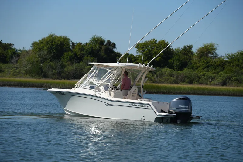 Slide: The Image of 2019 Grady-White Freedom 235 boat cruising on a calm lake with lush greenery. - 2