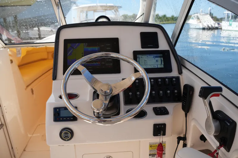 Slide: The Image of 2019 Grady-White Freedom 235 boat dashboard with steering wheel and navigation controls. - 22