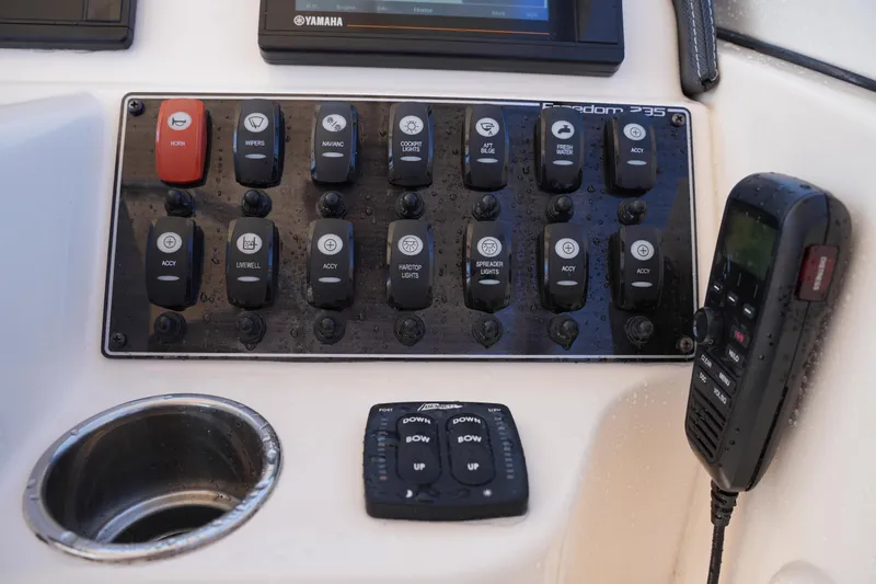 Slide: The Image of Control panel of a 2019 Grady-White Freedom 235 boat with switches and radio. - 25