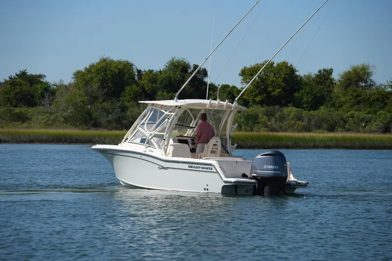 Slide: The Image of 2019 Grady-White Freedom 235 boat cruising on a calm lake with lush greenery. - 3