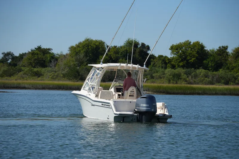 Slide: The Image of 2019 Grady-White Freedom 235 boat cruising on a calm lake with lush greenery. - 4