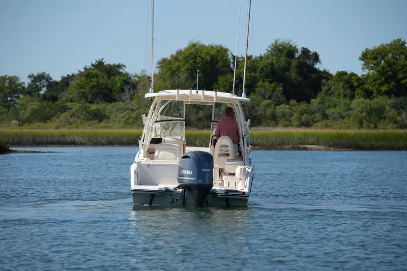 Slide: The Image of 2019 Grady-White Freedom 235 boat cruising on a serene lake with lush greenery. - 5