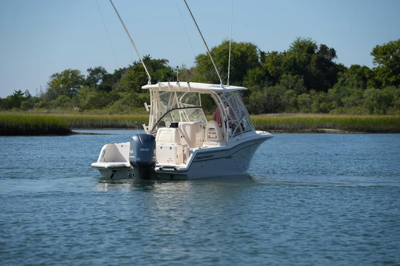 Slide: The Image of 2019 Grady-White Freedom 235 boat cruising on a serene lake with lush greenery. - 6