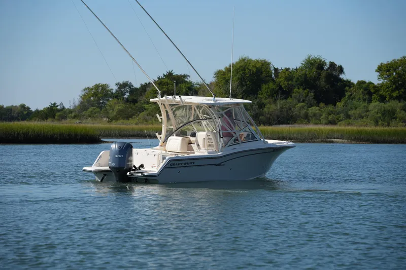 Slide: The Image of 2019 Grady-White Freedom 235 boat cruising on a serene lake with lush greenery. - 7