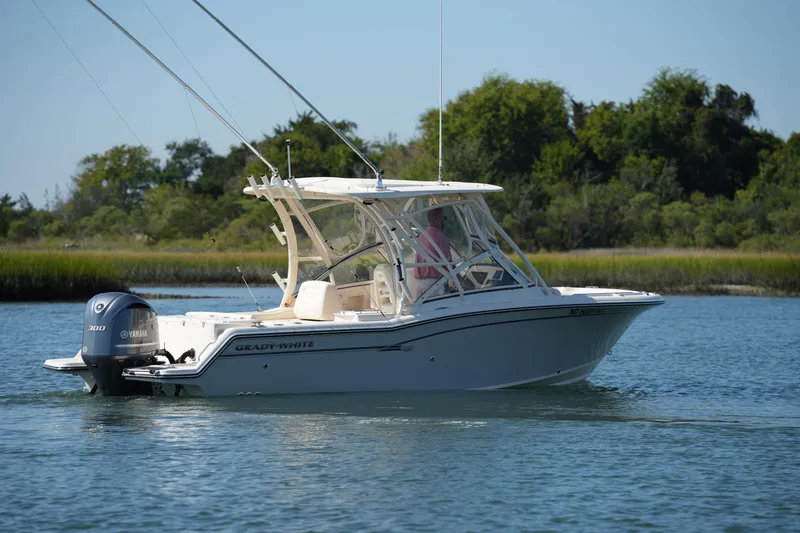 Slide: The Image of 2019 Grady-White Freedom 235 boat cruising on a serene lake with lush greenery. - 8