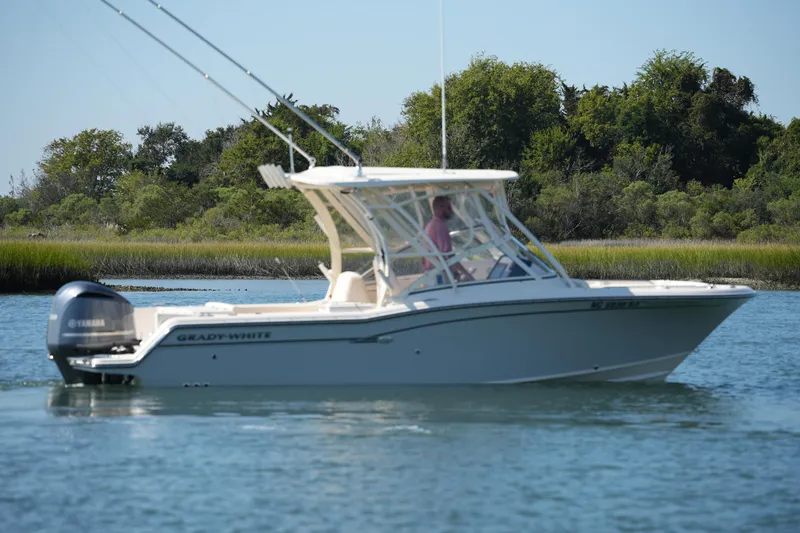 Slide: The Image of 2019 Grady-White Freedom 235 boat cruising on a calm lake with lush greenery. - 9