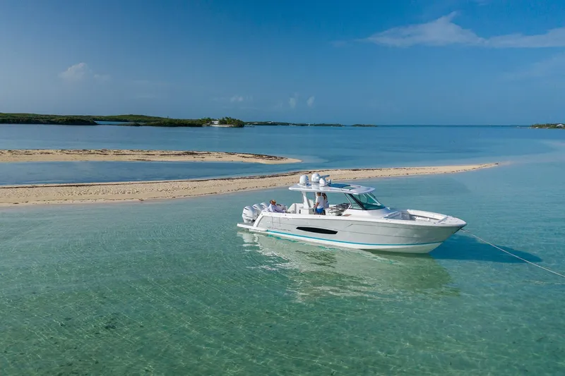 Slide: The Image of 2026 Regal 38 SAV boat anchored in clear turquoise waters near a sandy island. - 4
