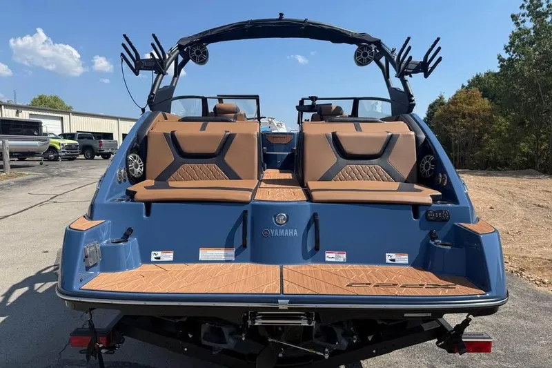 Slide: The Image of 2026 Yamaha Boats 222XE, rear view, blue exterior, brown seating, parked outdoors. - 5