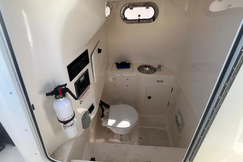 Slide: The Image of 2016 Pursuit S 280 Sport boat interior with toilet, sink, and fire extinguisher. - 11