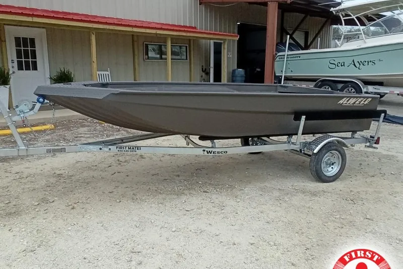 Slide: The Image of 2025 Alweld 1548 Invader boat on trailer, parked outside a building. - 1