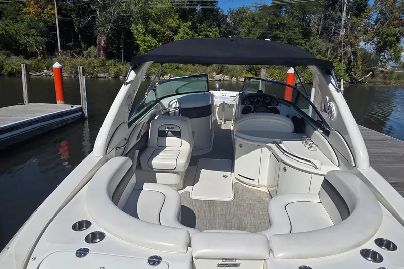 Slide: The Image of 2006 Sea Ray 290 Select EX boat interior with seating, docked by a wooded shoreline. - 29