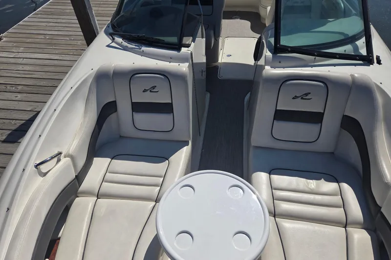 Slide: The Image of 2006 Sea Ray 290 Select EX boat interior with seating and table, docked by wooden pier. - 3