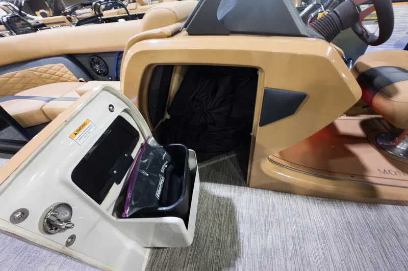 Slide: The Image of 2026 Godfrey Monaco 235 Split Bench interior storage compartment with beige seating and steering wheel. - 11