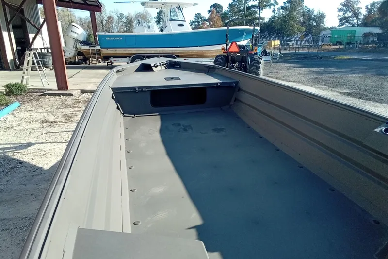 Slide: The Image of 2025 Alweld 1648VV Marsh boat interior, parked outdoors near a blue vessel. - 14