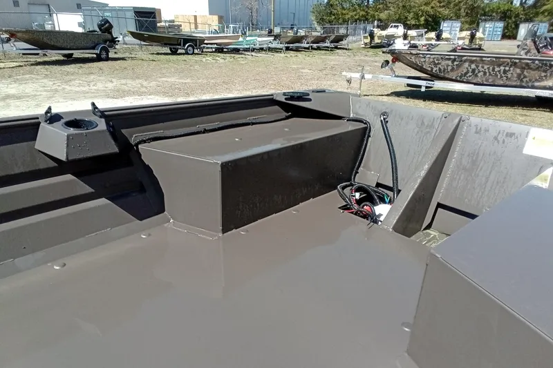 Slide: The Image of 2025 Alweld 1648VV Marsh boat interior, docked near a blue boat on a trailer. - 8