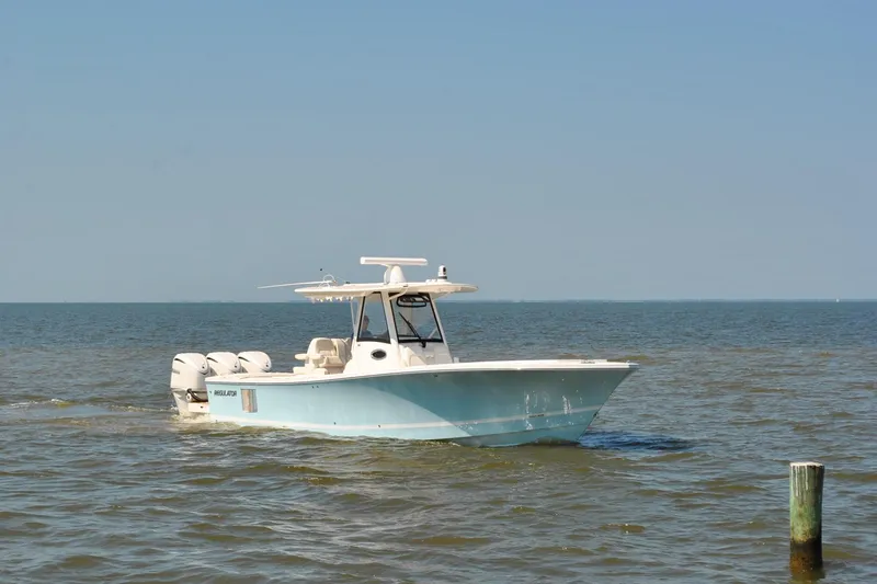 Slide: The Image of 2025 Regulator 34 Center Console boat cruising on open water under clear blue sky. - 13