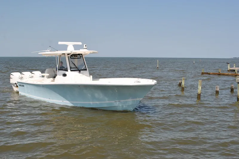 Slide: The Image of 2025 Regulator 34 Center Console boat on calm water, showcasing sleek design and powerful engines. - 19