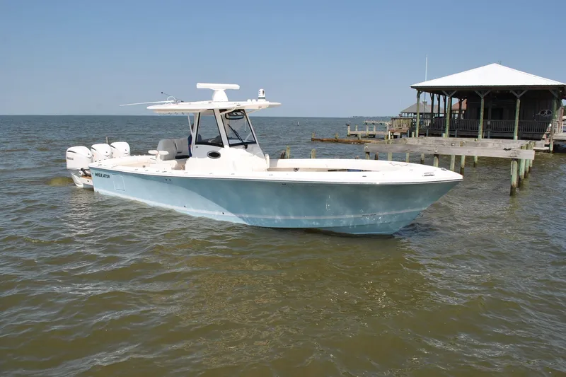 Slide: The Image of 2025 Regulator 34 Center Console boat on calm waters near a dock. - 20